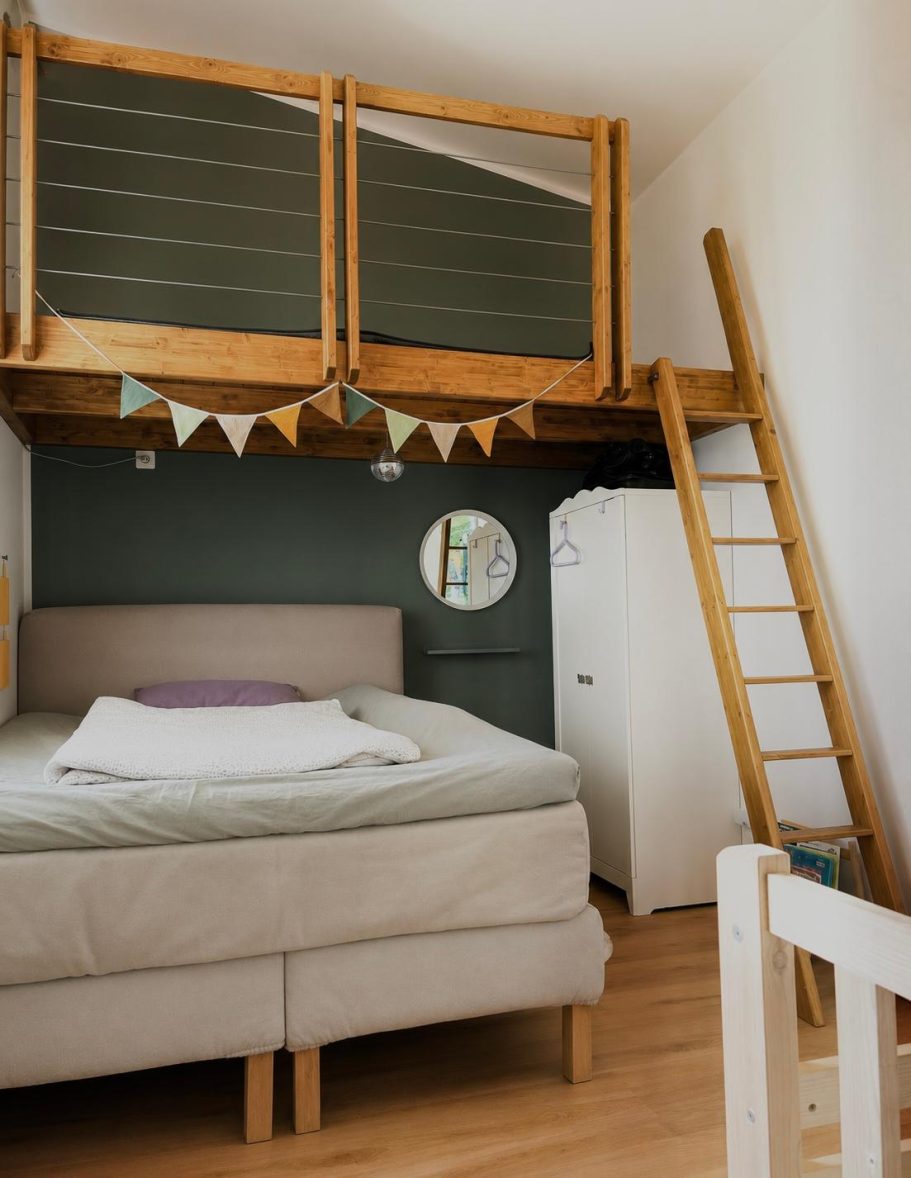 Schlafzimmer 2 mit Empore Helles Schlafzimmer mit Hochbett, Leiter, minimalistischem Design und runder Wandspiegel.