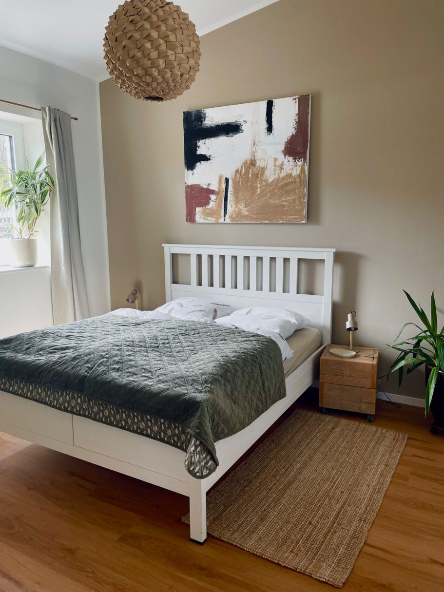 Schlafzimmer 1 Helle Schlafzimmer mit Doppelbett, Kunstwerk an der Wand und Pflanzen.
